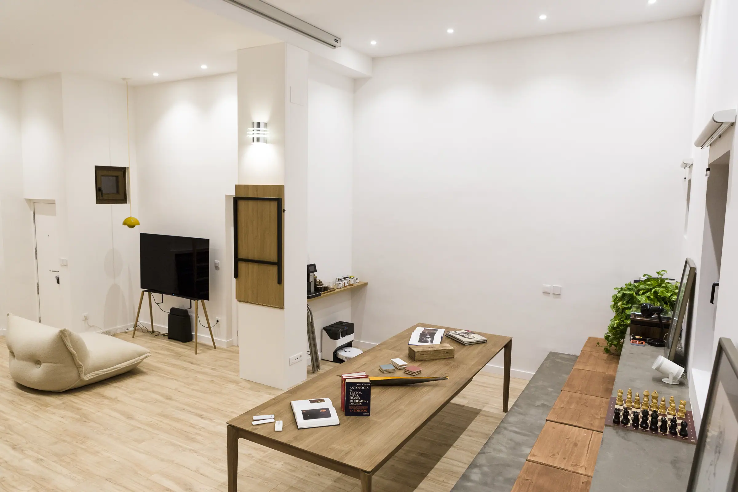 Rincón de la sala con puf, televisión y banco